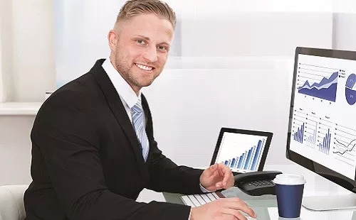 Man on a computer that has various graphs on the screen